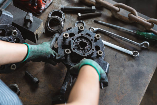 Industrial plant worker repairing car parts in auto repair workshop - Mechanical engineer inspecting and adjusting vehicle part - Manufacturing factory, student apprentice and skilled work concept